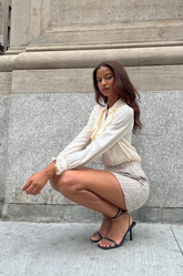 a lady in a white bow tie neck shirt and a tweed mini skirt